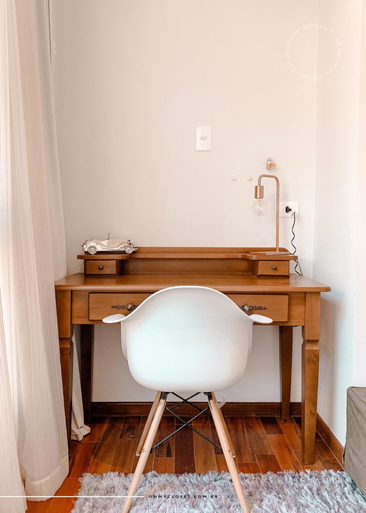 Área de trabalho com mesa rústica e cadeira Eifel branca na entrada da suíte master.