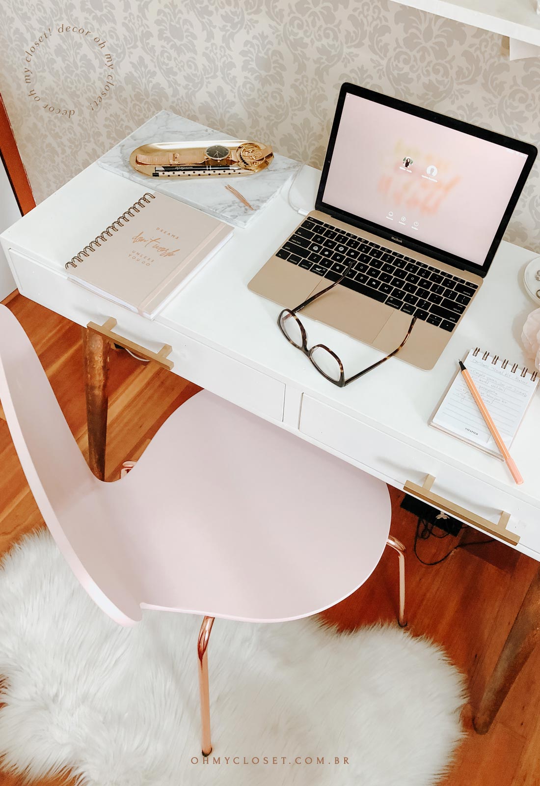 Home office com cadeira rosa, ferragens rose, mesa branca de madeira com pé palito.