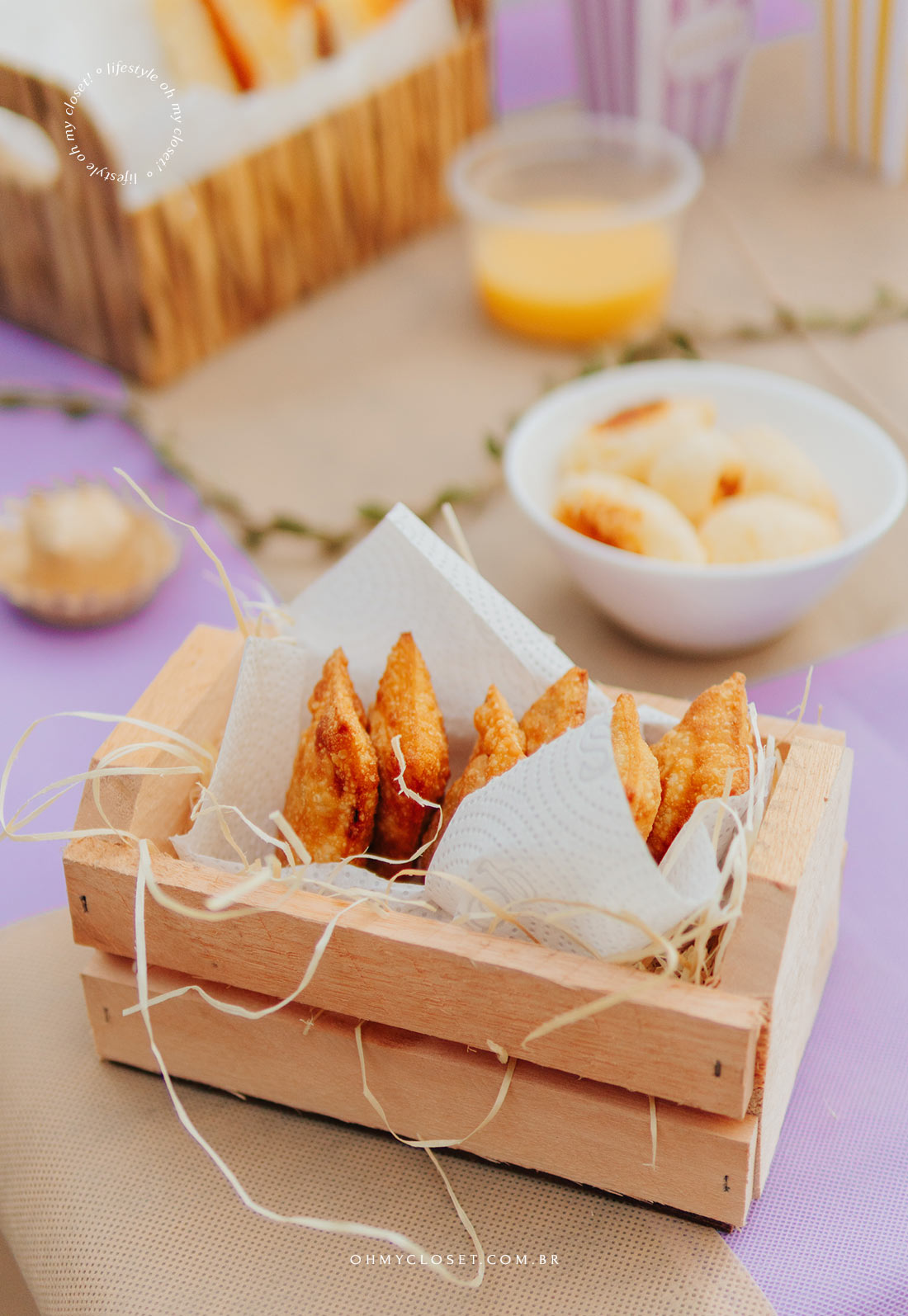 Detalhe dos pastéis na mesa de comida da festa junina em apartamento com pães de queijo ao fundo