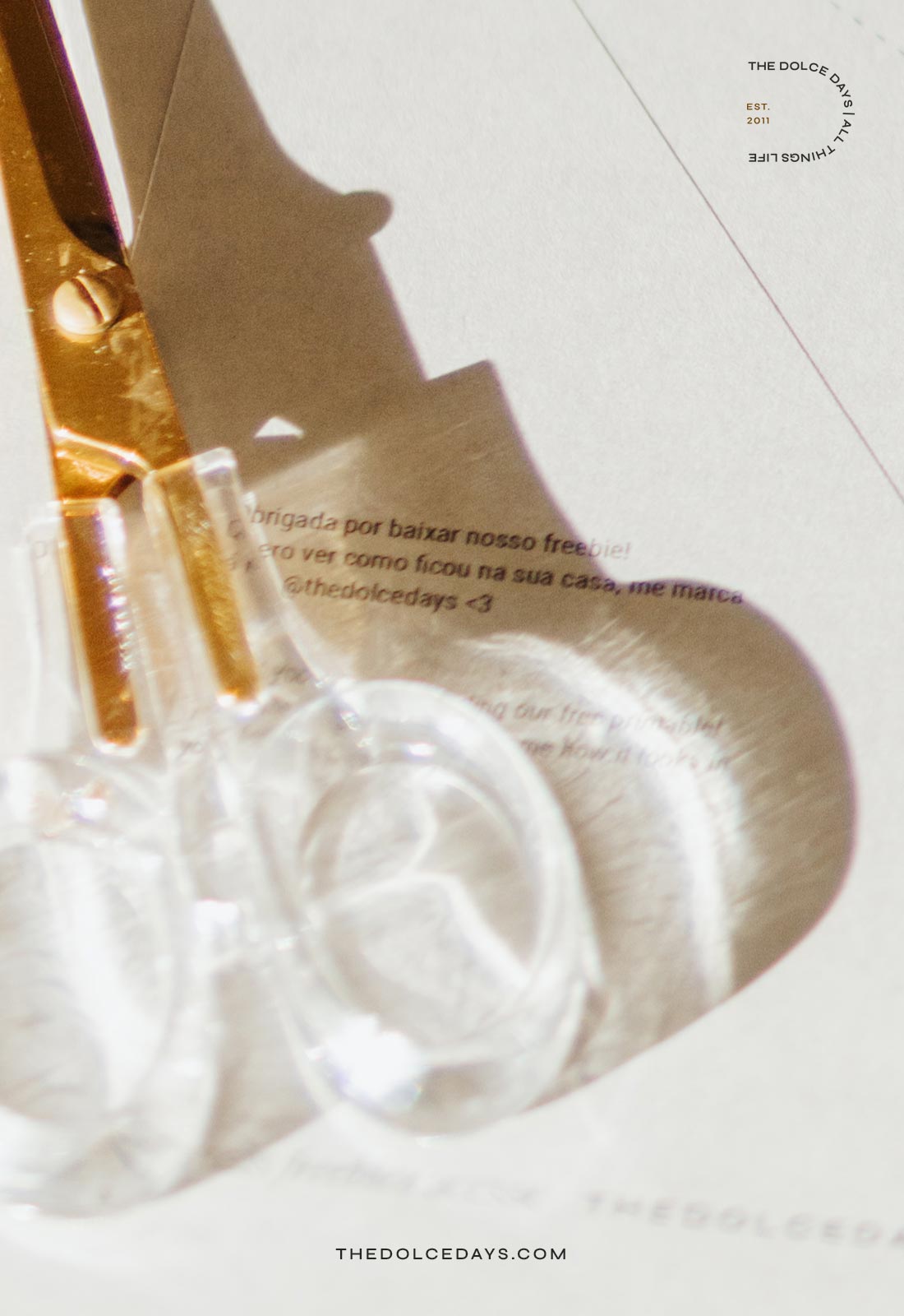 Detalhe tesoura dourada com cabo transparente.